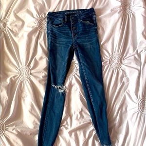 Ripped dark-wash jeans with multiple buttons.